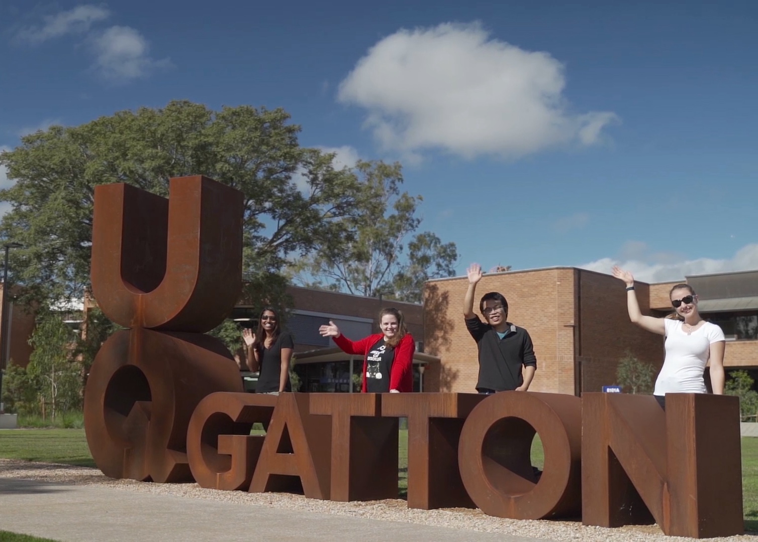 students waving in front of UQ Gatton sign