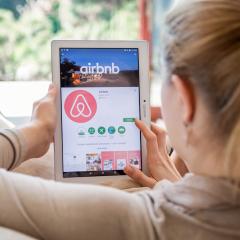 A woman browsing Airbnb's website on a tablet